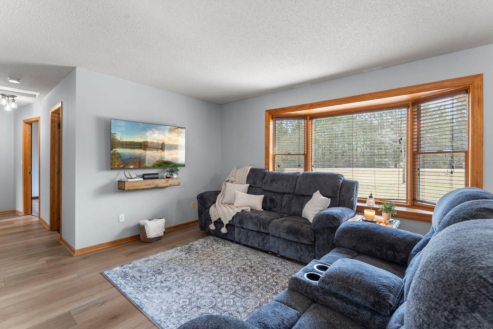 Inside, you’re greeted by a spacious, front-facing living room filled with natural light from a large picture window.