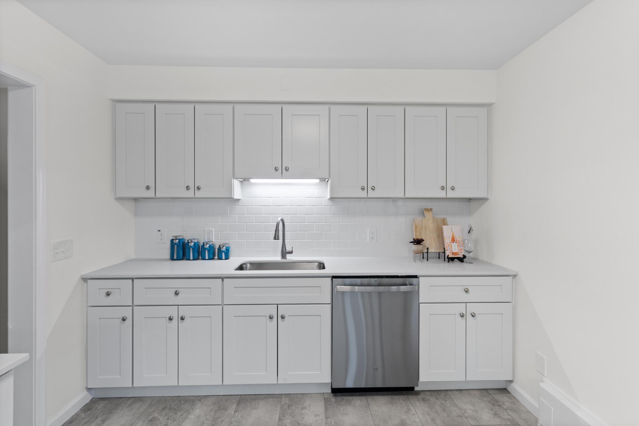 Brand new kitchen with white cabinets and stainless steel appliances.