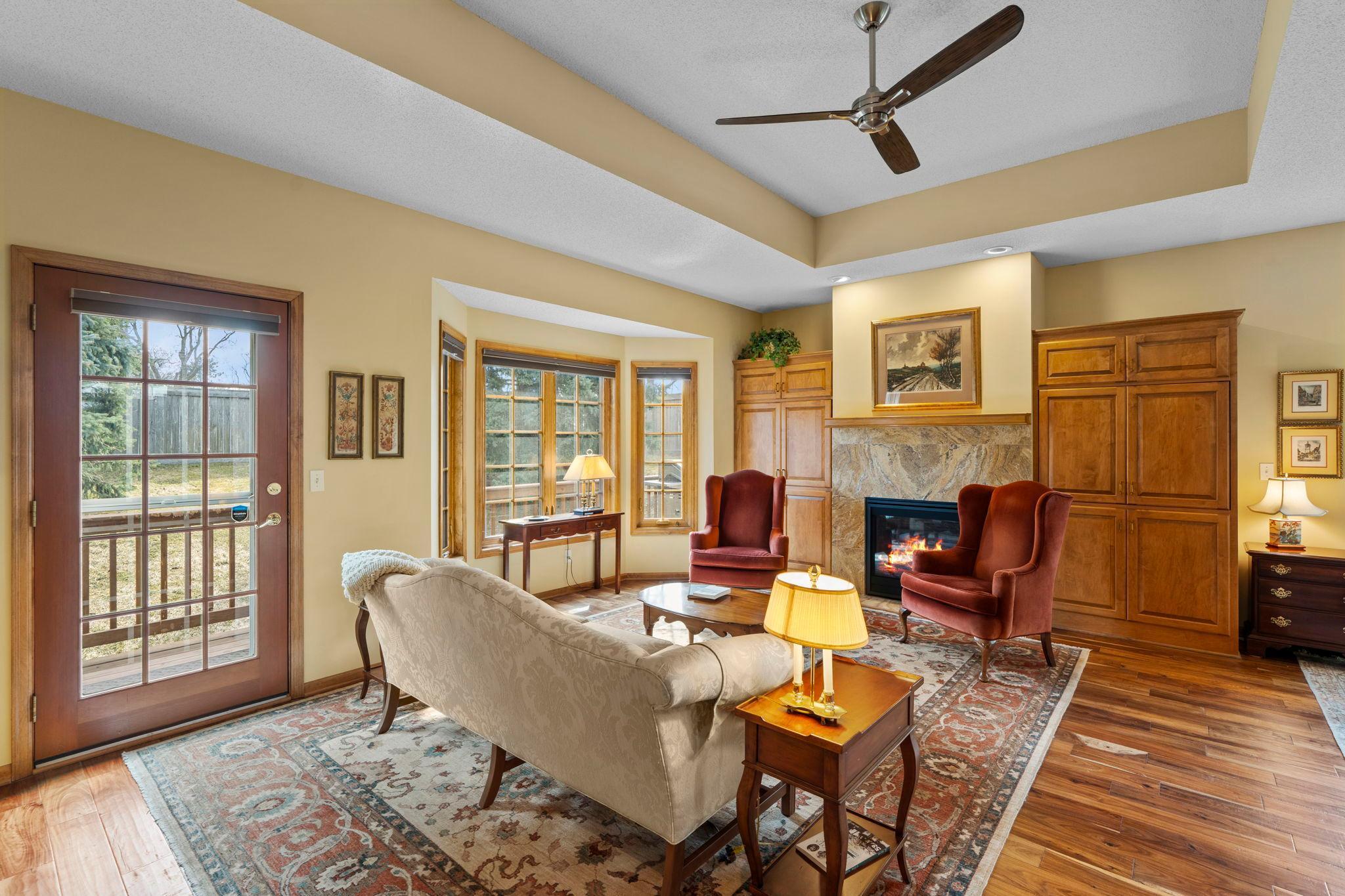 The living room features a bay window with backyard views and tray ceilings that add architectural depth.
