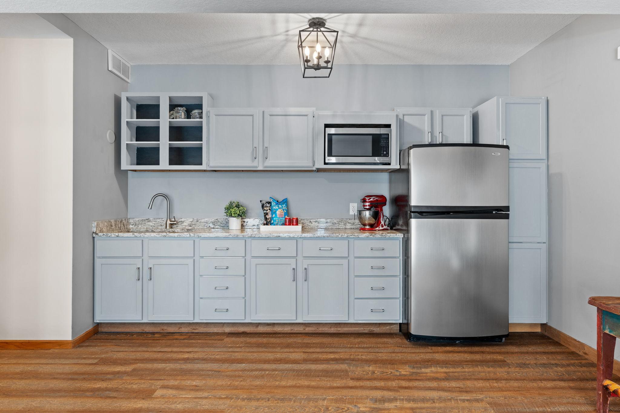 New kitchen in the lower level added 2022 with stainless steel refrigerator, granite countertops, microwave and lots of storage