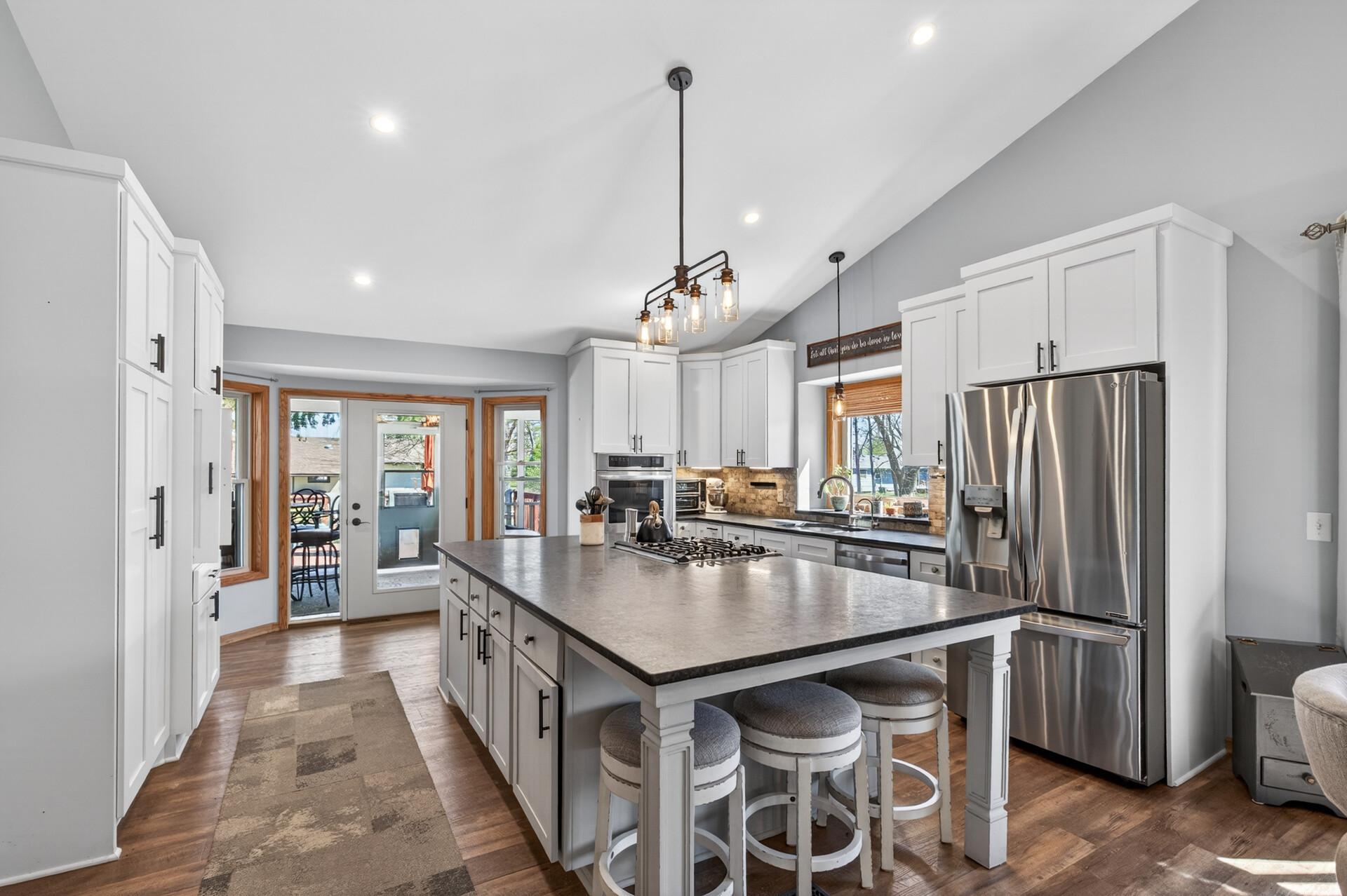 This kitchen has it all! Huge center island with seating, stainless appliances including range, wall ovens, pantry cabinet with beverage station & French door that opens to the screened porch