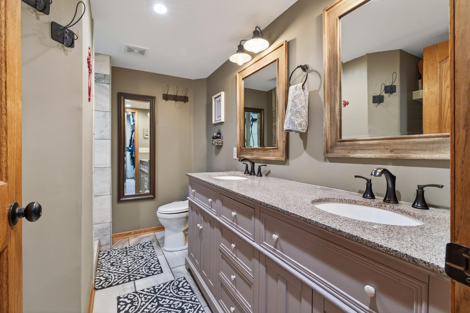 Primary 3/4 tile bath with dual sink vanity with granite counter top, storage & a walk-in shower