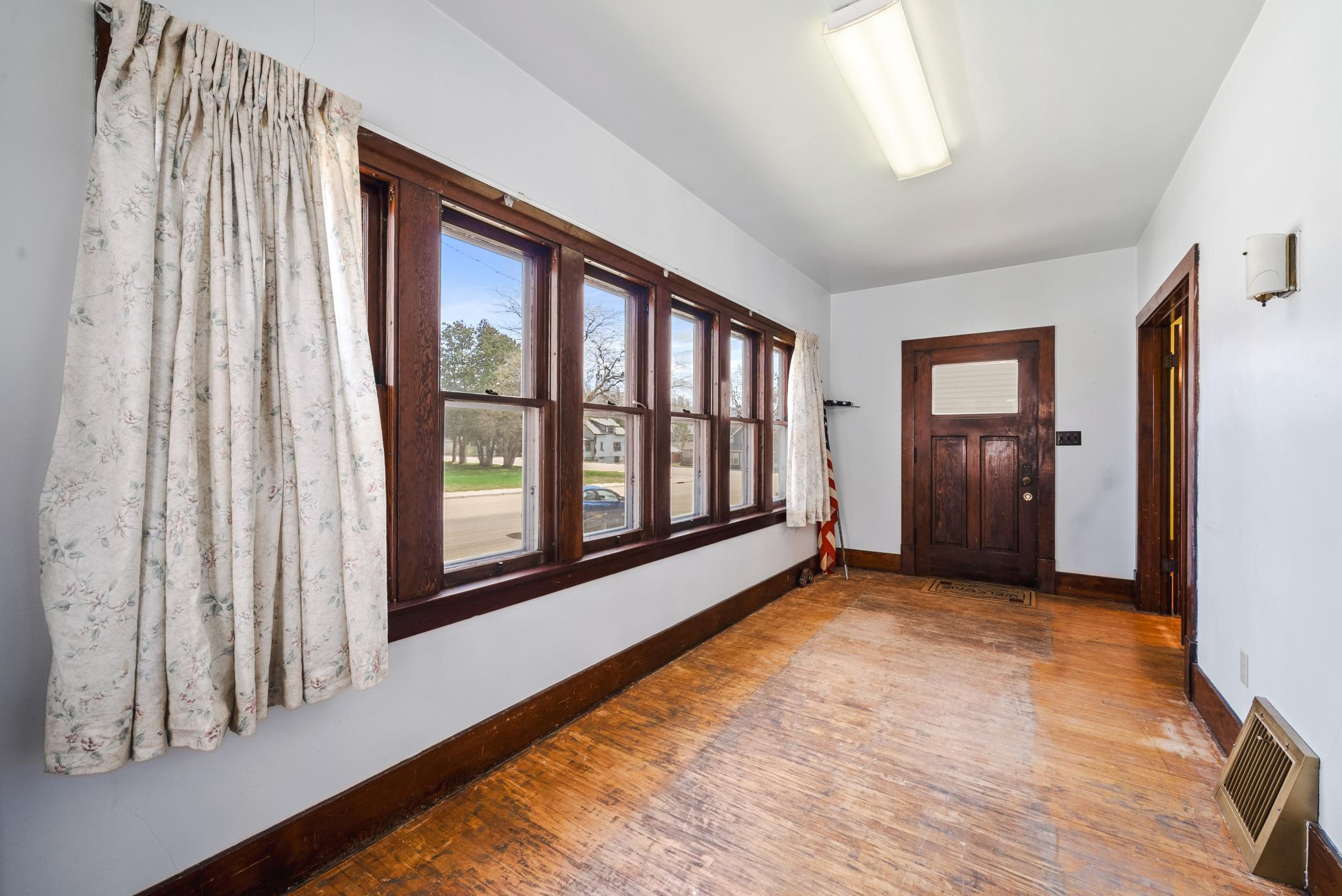 Step into the inviting front sunroom lined with windows, leading into spacious living and dining areas featuring hardwood floors!