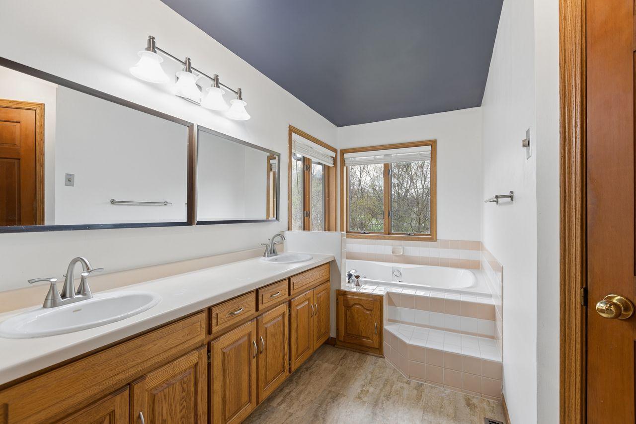Indulge in luxury with this ensuite modern bath showing off a corner Jacuzzi tub with amazing views