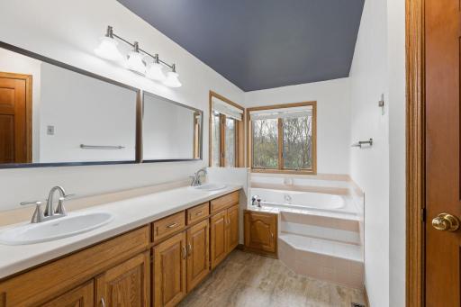 Indulge in luxury with this ensuite modern bath showing off a corner Jacuzzi tub with amazing views