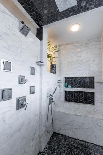 Walk in shower has two shower head options - one with a built in bench.