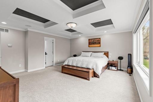 Spacious primary suite with coffered ceiling.