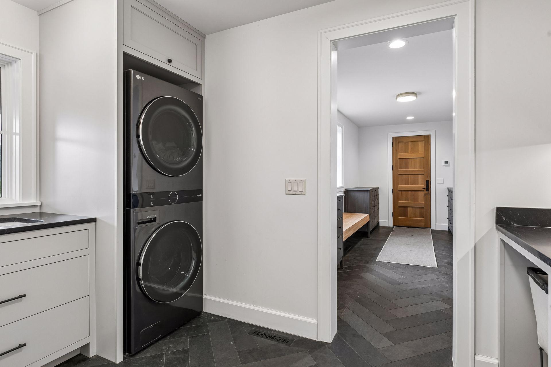 Generous laundry room with heated slate flooring, utility sink, and ample storage, flowing seamlessly into the mudroom.