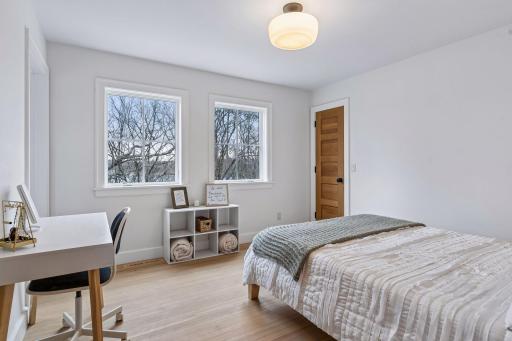 The second upper level bedroom, with hardwood flooring, ample natural light from two windows, overhead light, and a generous walk in closet.