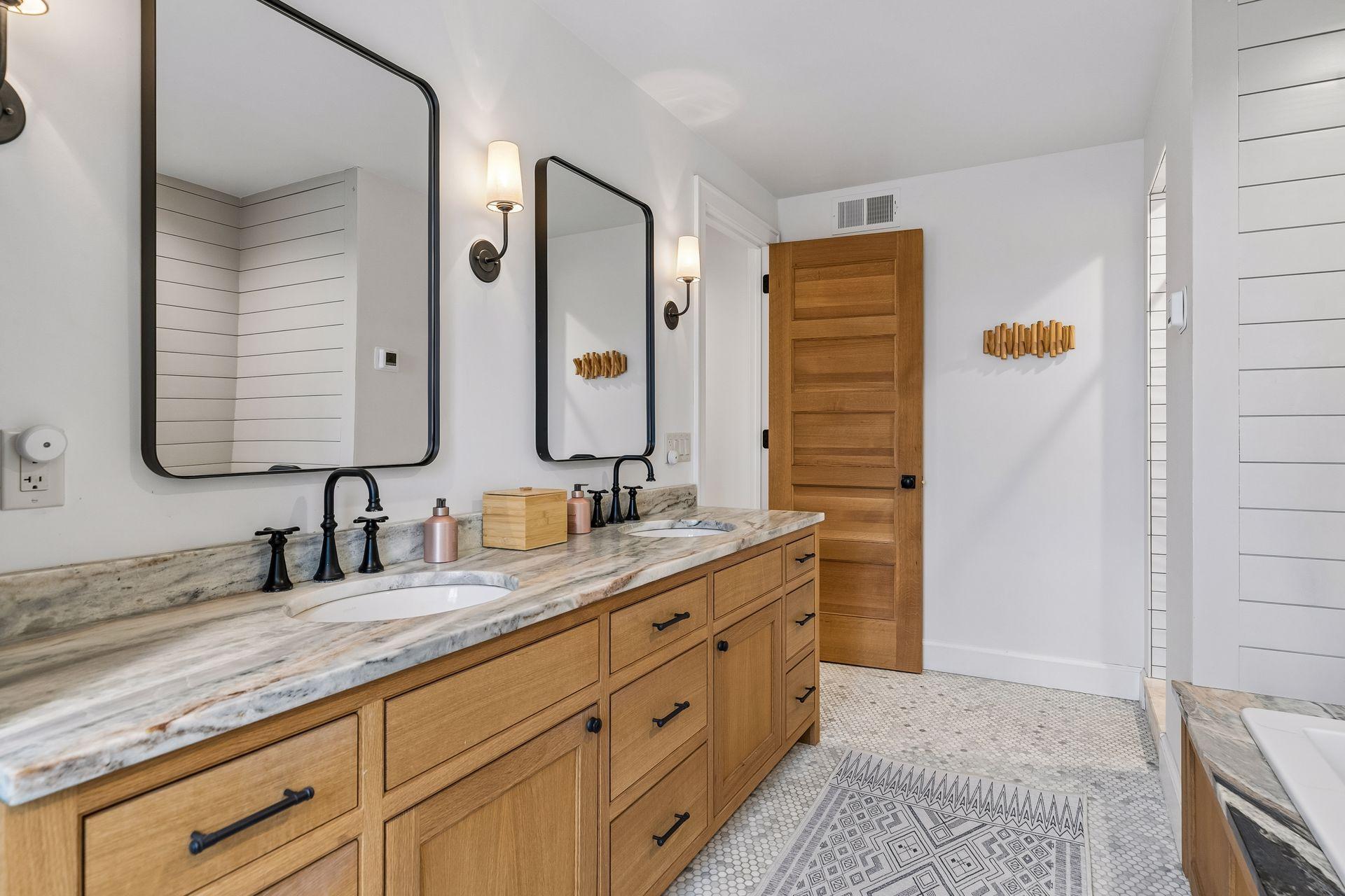 Primary bath with a double sink vanity, heated tile floors, natural light from a window, and a separate soaking tub and shower.
