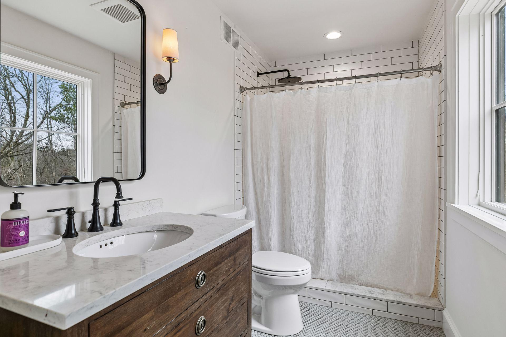 The private ensuite bath features heated tile floors, a vanity sink, window for natural light, and a stylish tiled shower.