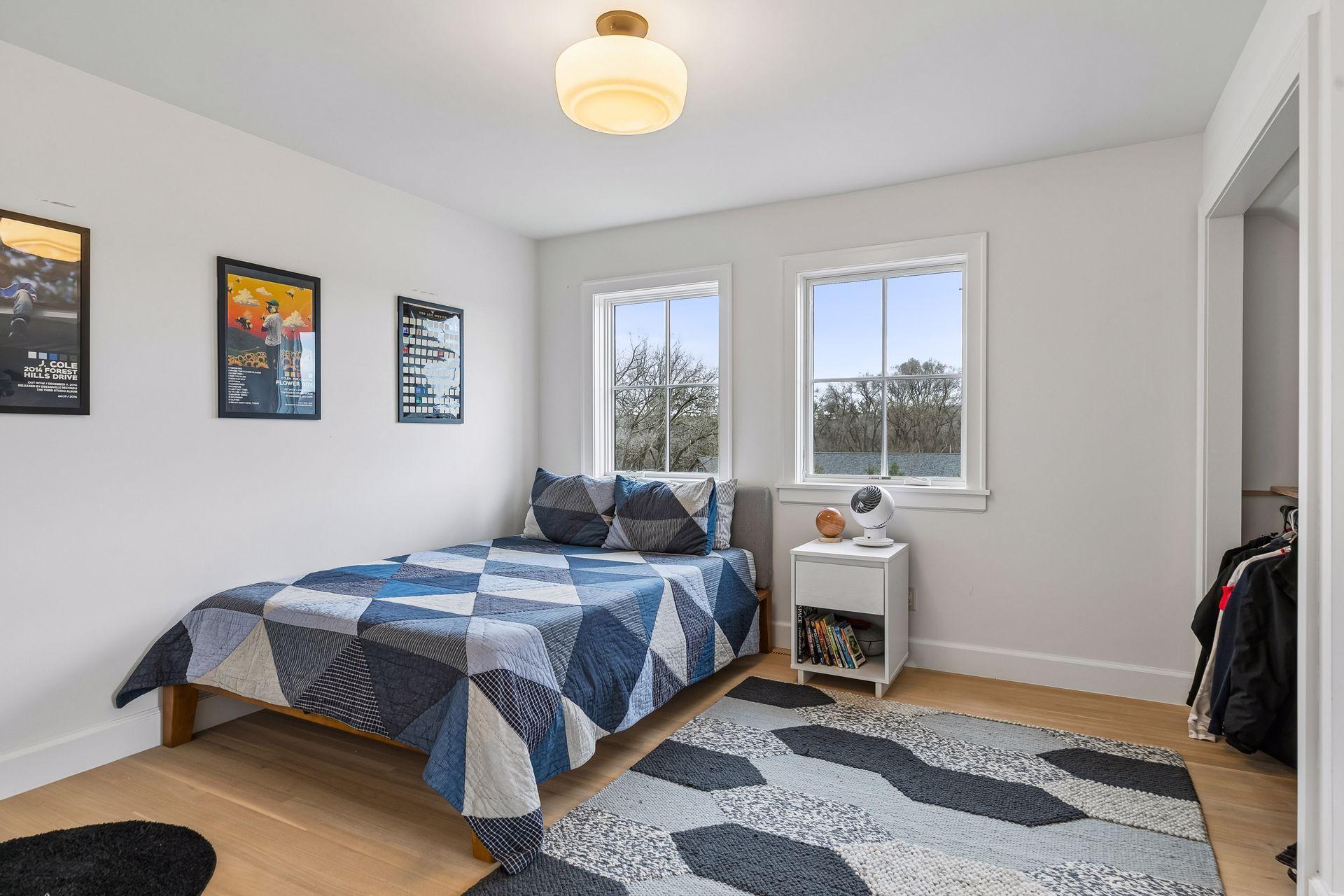 The first of three upper level bedroom features hardwood floors, overhead lighting, three windows, and a practical closet.