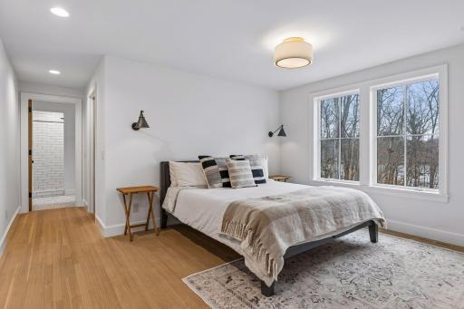 Convenient primary bedroom on the main level with hardwood flooring, recessed and overhead lighting, multiple bright windows, a generous walk in closet, and an attached ensuite full bathroom.