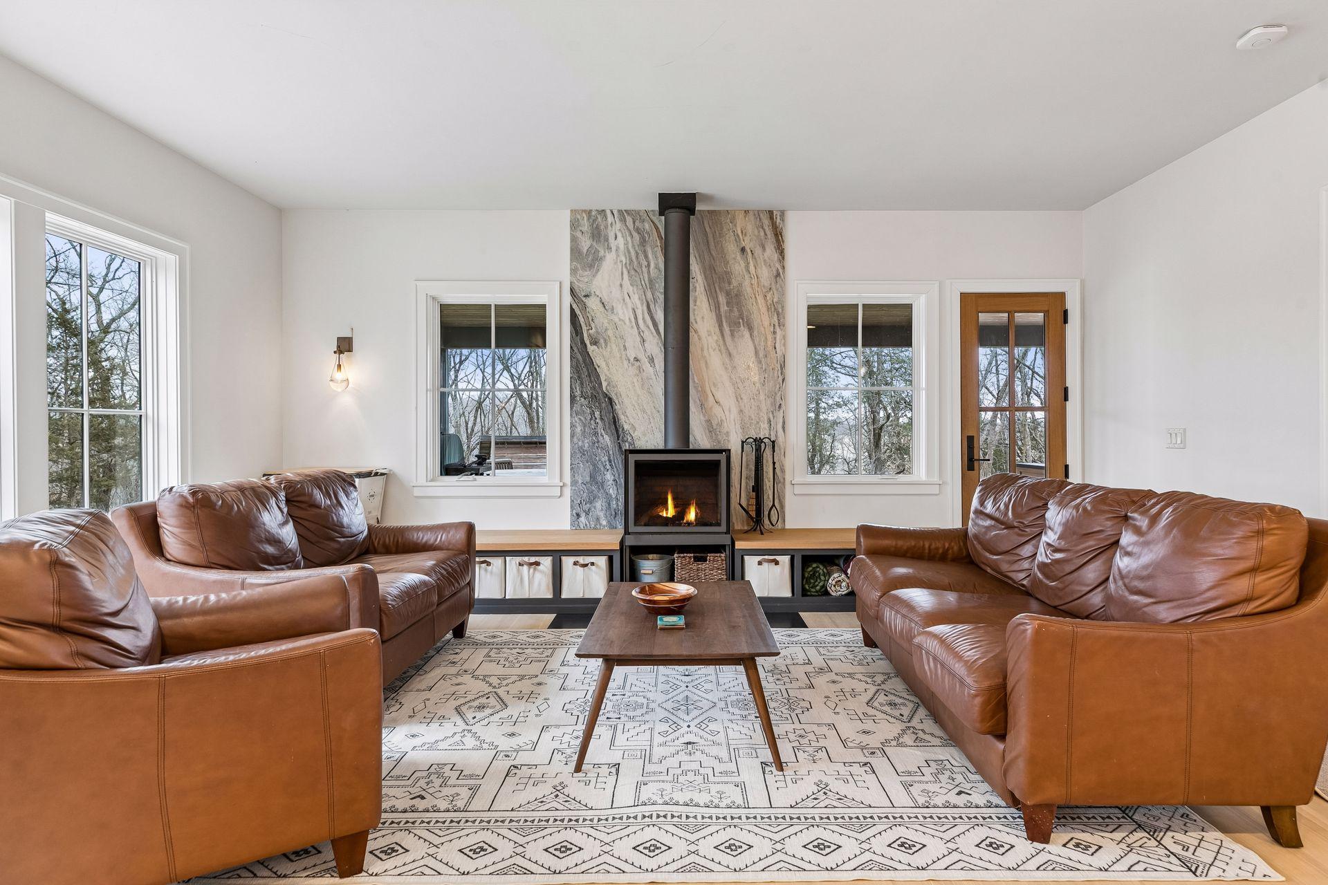 A bright and inviting living room with hardwood floors, ample built ins, a cozy wood burning stove, and generous windows that enhance the open, airy feel.
