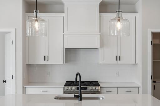 Kitchen showcases 42" white upper cabinets, a statement wood hood, and elegant pendant lighting over the island.