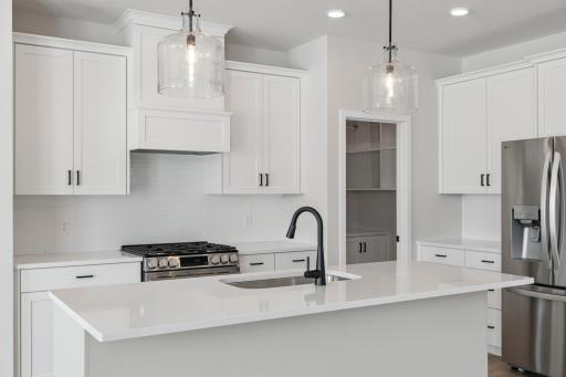 Quartz countertops and tile backsplash add a modern, refined touch to the kitchen.