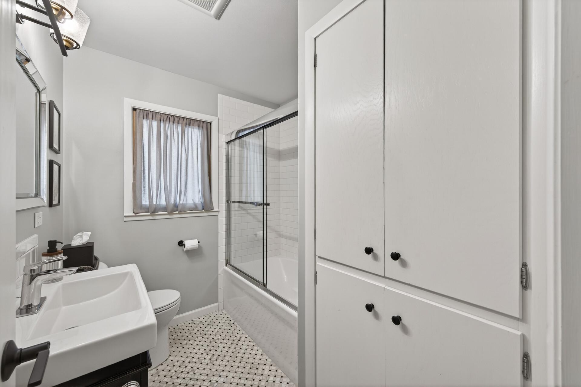 Main floor full bathroom with tile floor and shower surround and linen closet.