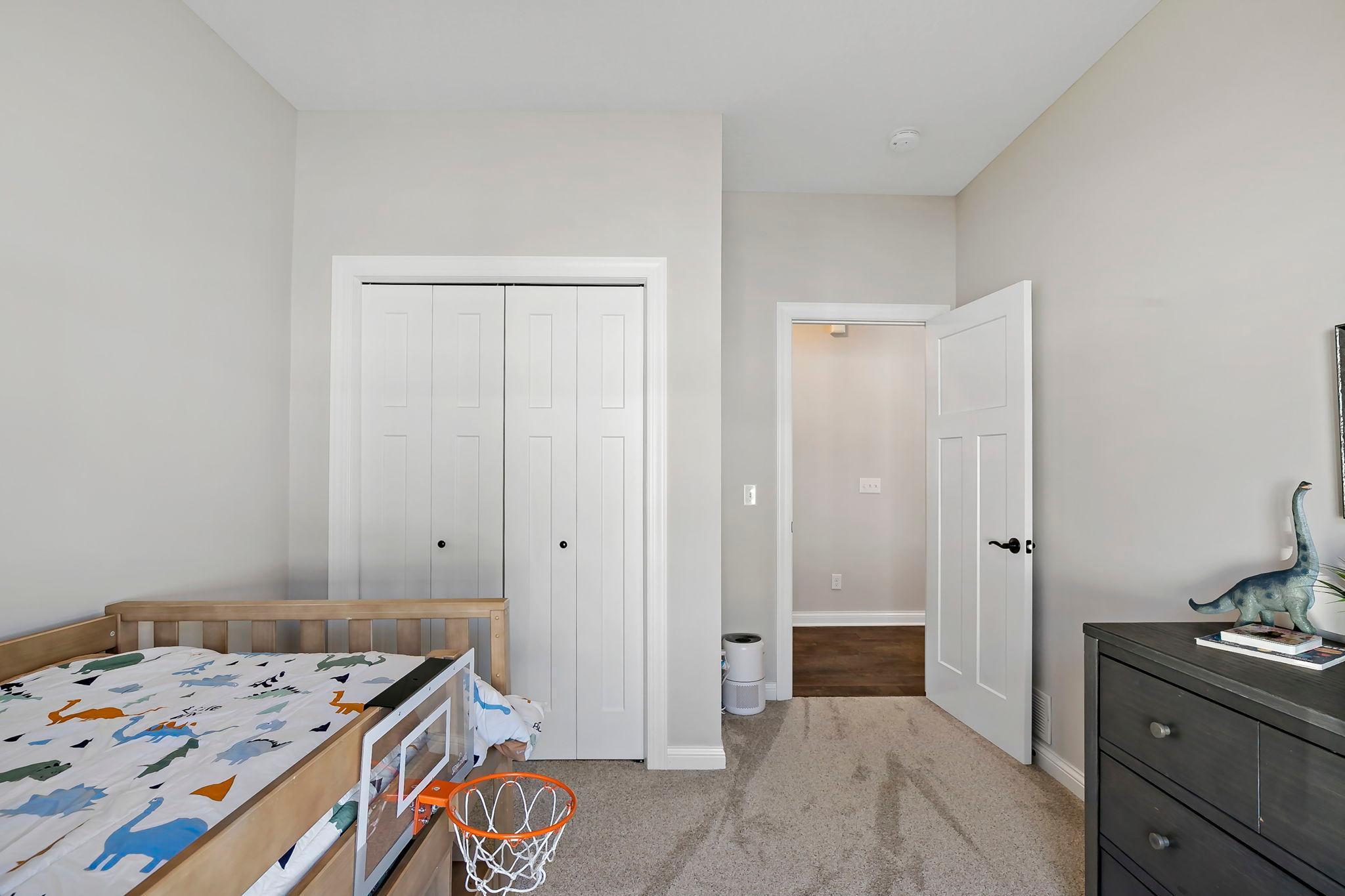 Spacious child’s bedroom with ample closet space and soft neutral finishes.