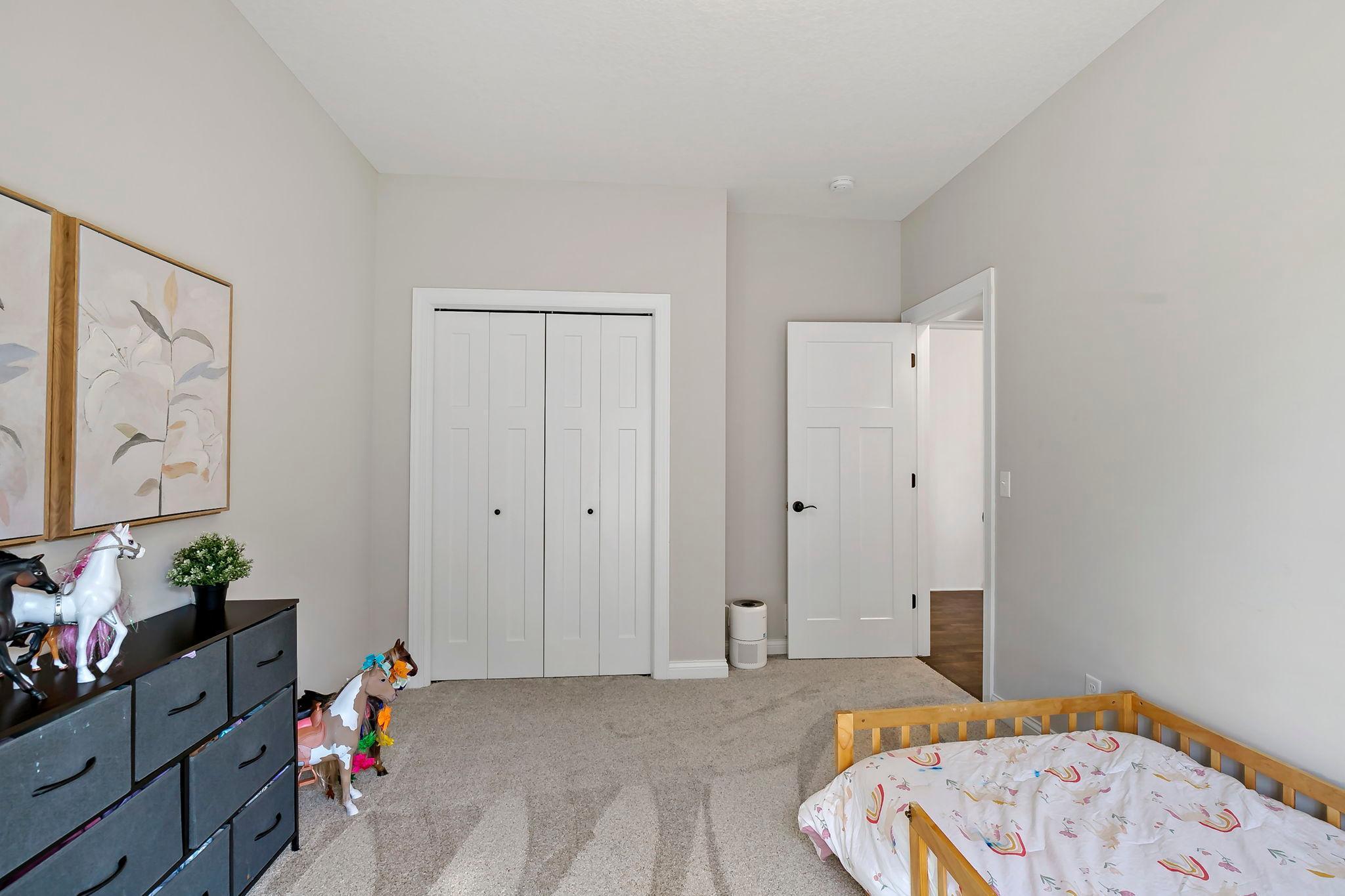 Light-filled bedroom with soft carpeting, spacious closet, and charming decor.