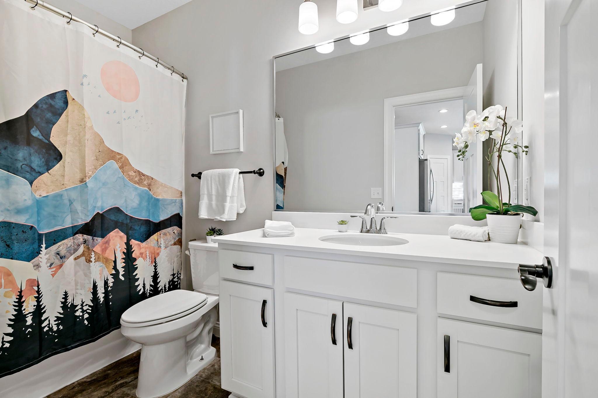 Bright bathroom with modern vanity, large mirror, and stylish decor.