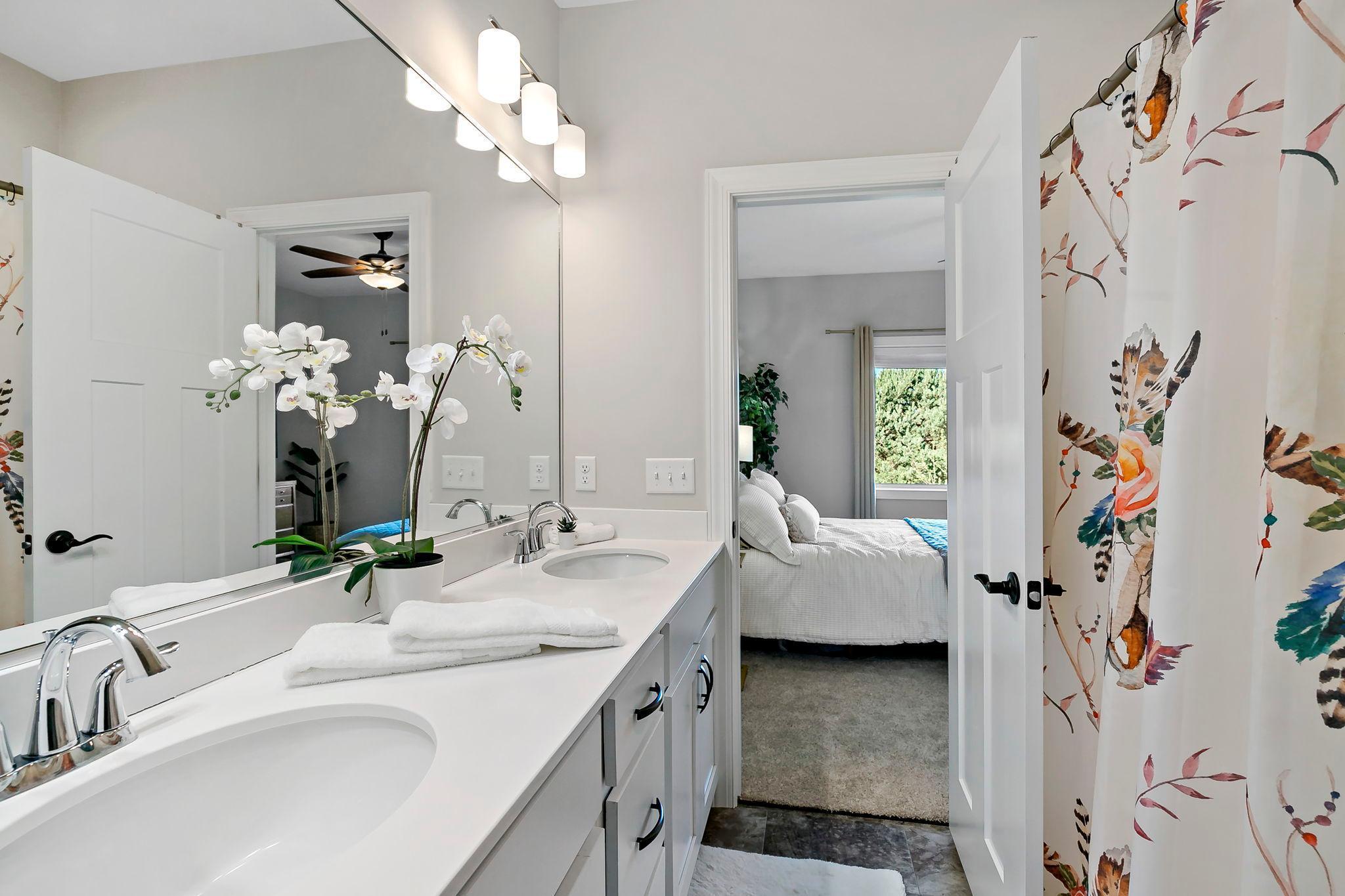 Modern bathroom with dual sinks, sleek lighting, and direct access to the bedroom.