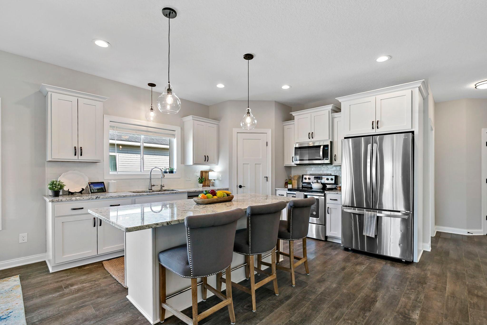 Modern kitchen with granite island, stainless steel appliances, and pendant lighting.