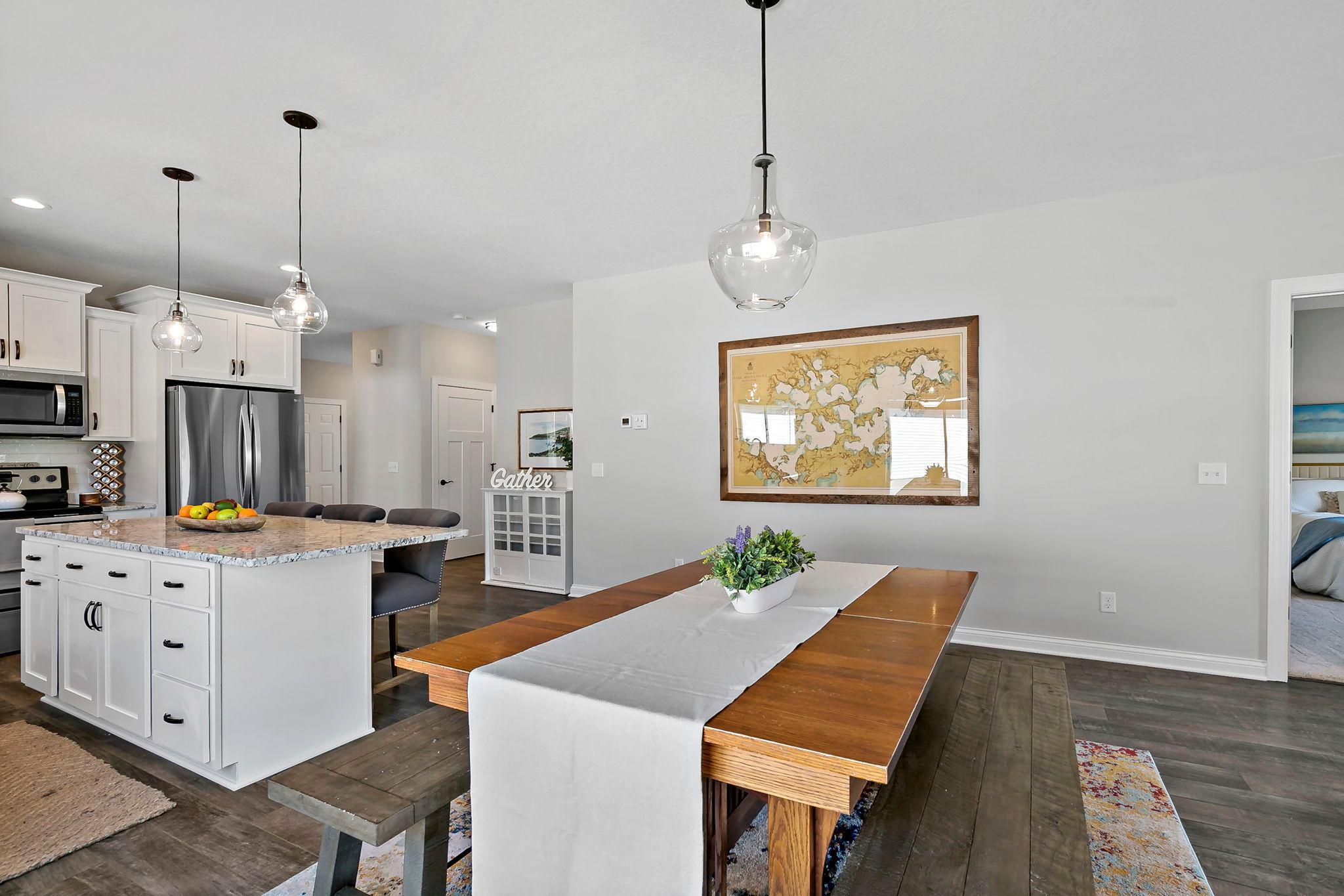 Bright open-concept kitchen and dining space with large island and contemporary lighting.