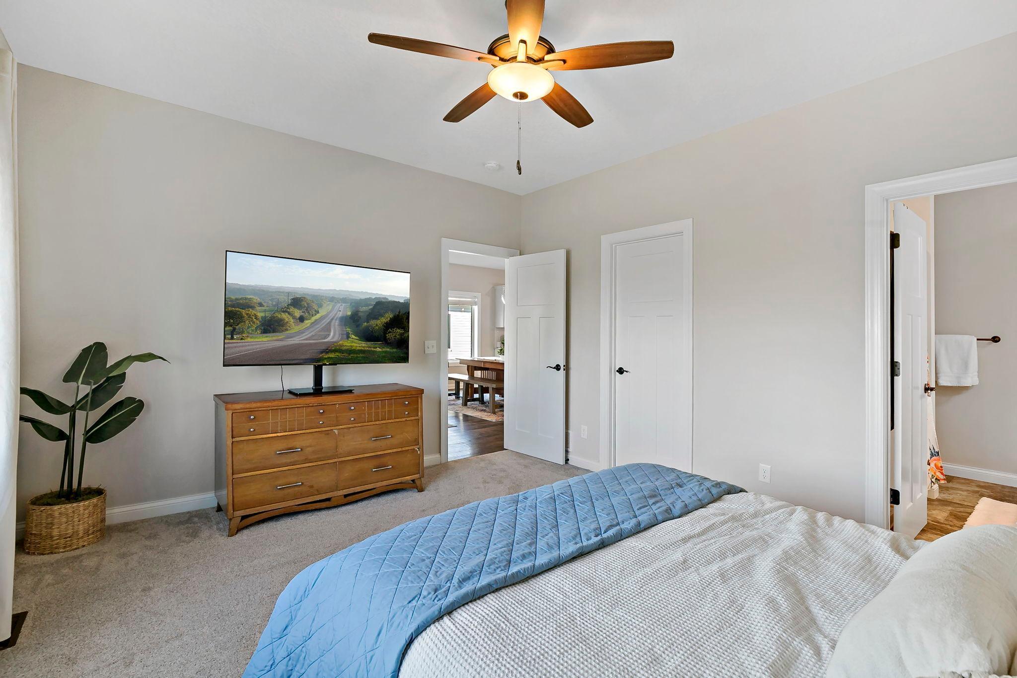 Spacious bedroom with ceiling fan, ensuite access, and ample closet storage.