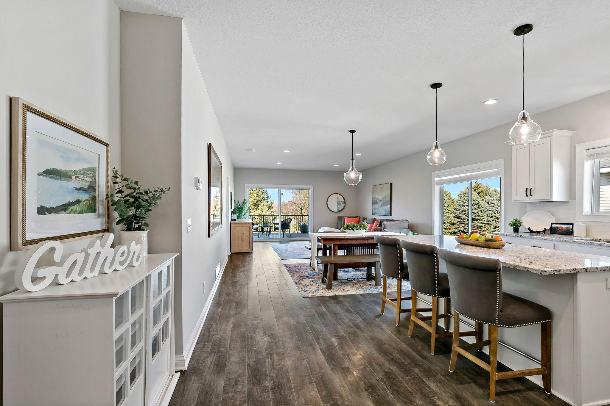 Open-concept living and dining area with modern kitchen island and deck access.