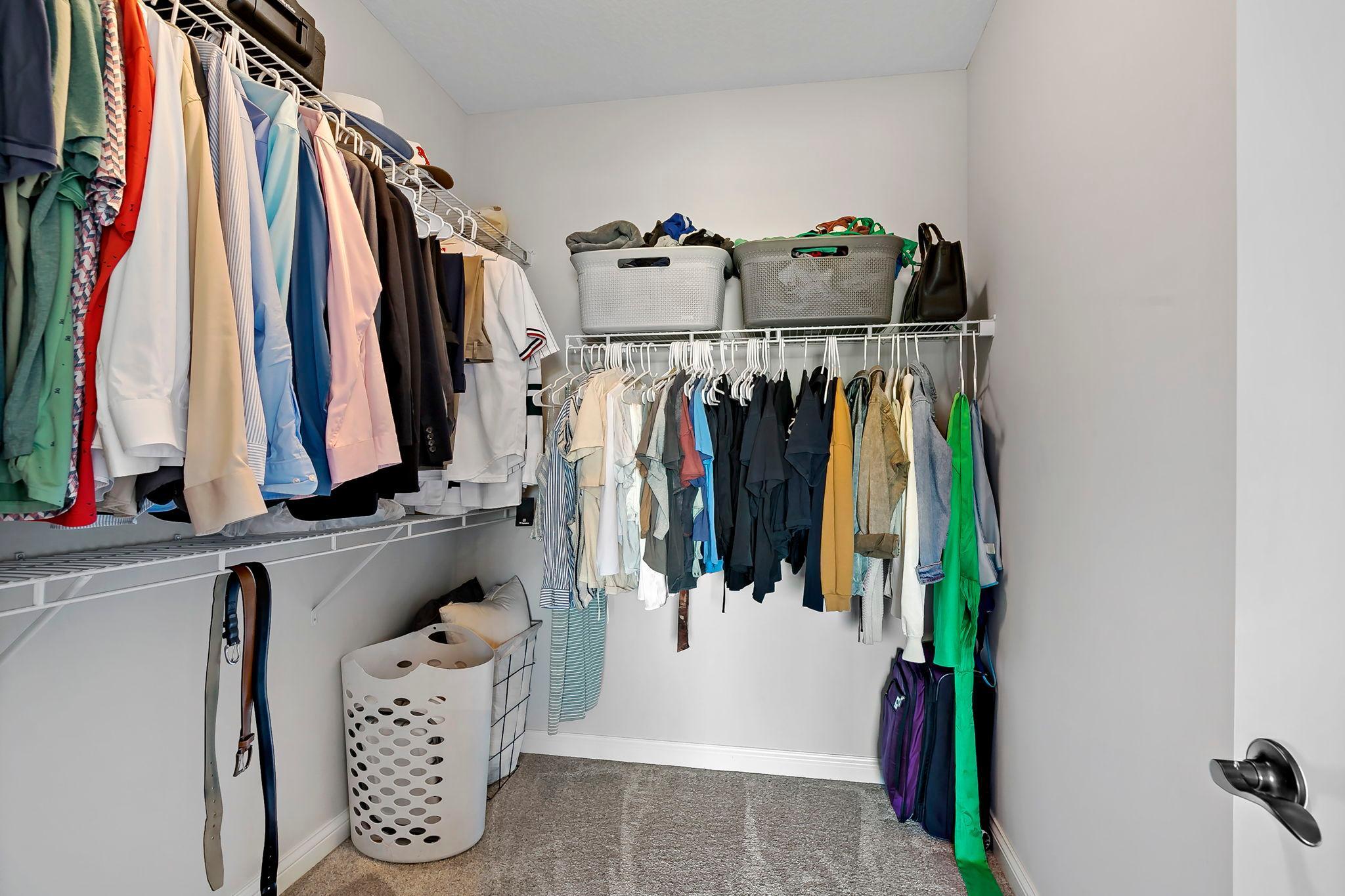 Organized walk-in closet with ample hanging space and convenient storage shelves.