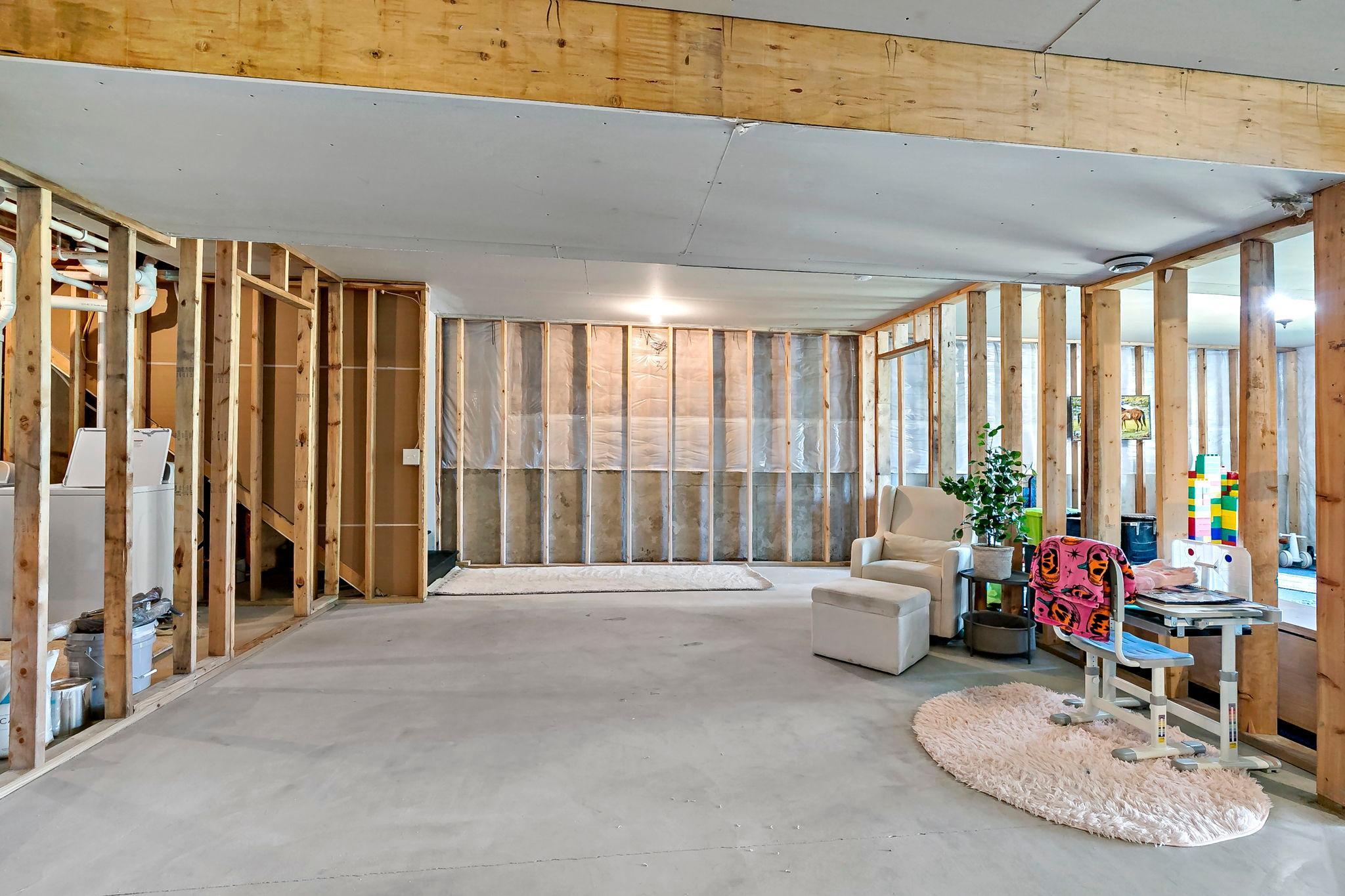 Expansive unfinished lower level with framed walls and flexible space for future finishing.