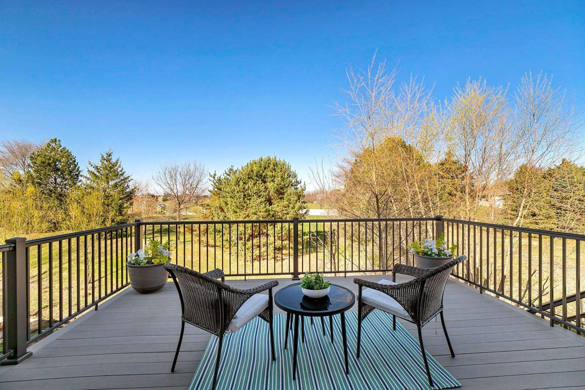 Cozy deck seating area with scenic views of trees and open green space.