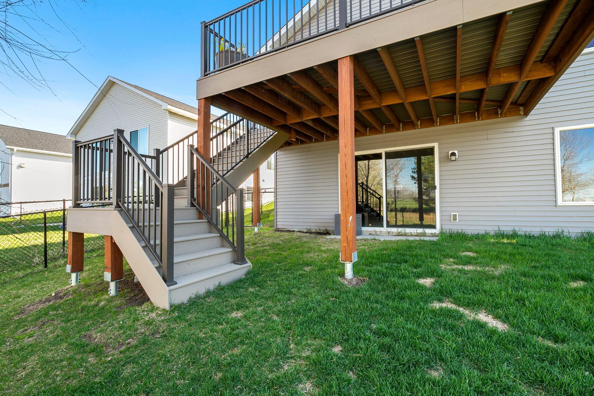 Staircase leading to an elevated deck with a sliding glass door opening to the backyard.