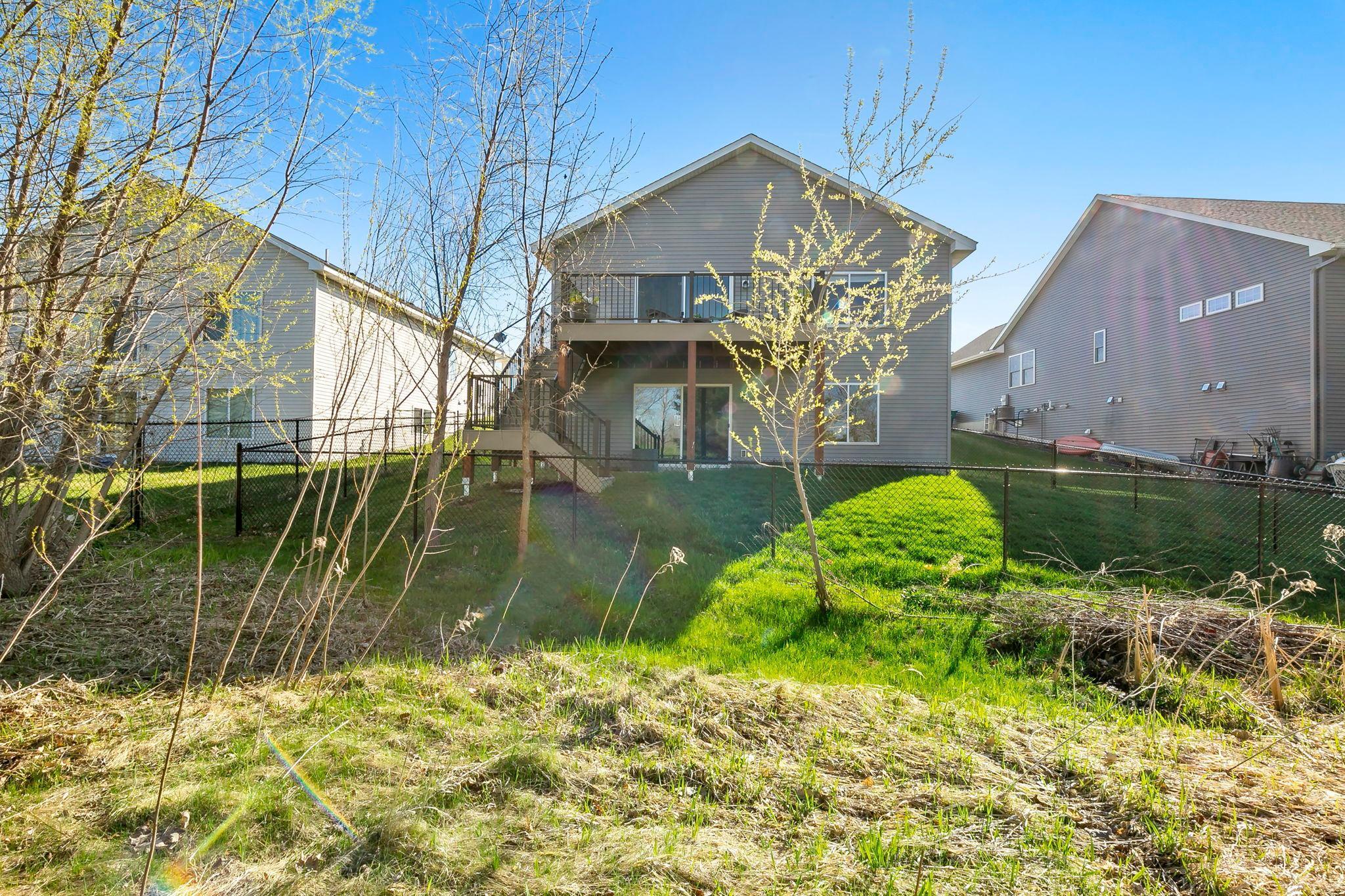 Rear view of neighboring homes with elevated decks overlooking fenced, grassy backyards.