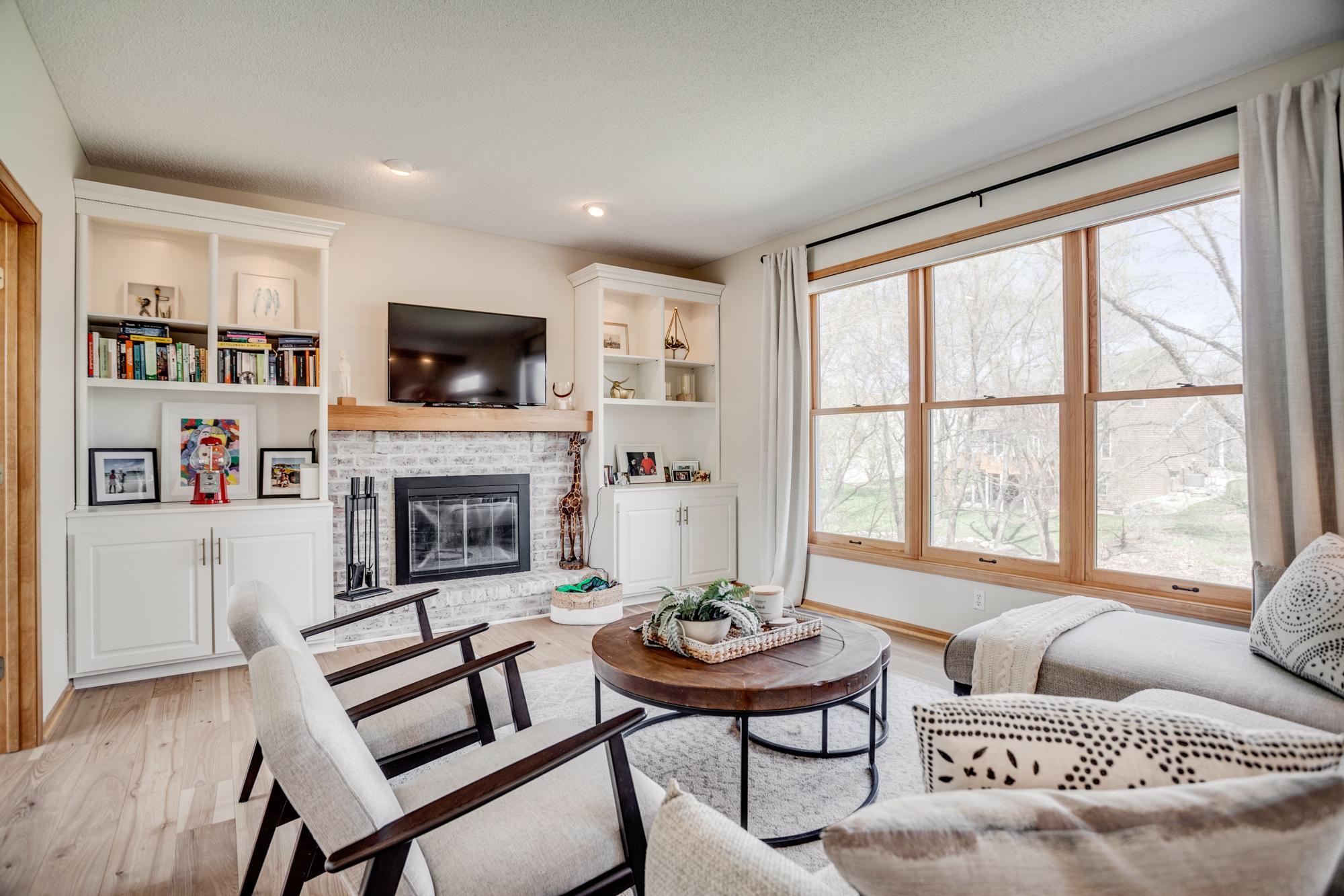 The family room features a wood burning fireplace with new mantel, surround & fireplace doors + built-in cabinetry, creating a warm and inviting gathering space. Expansive windows frame peaceful pond views and fill the space with natural light.