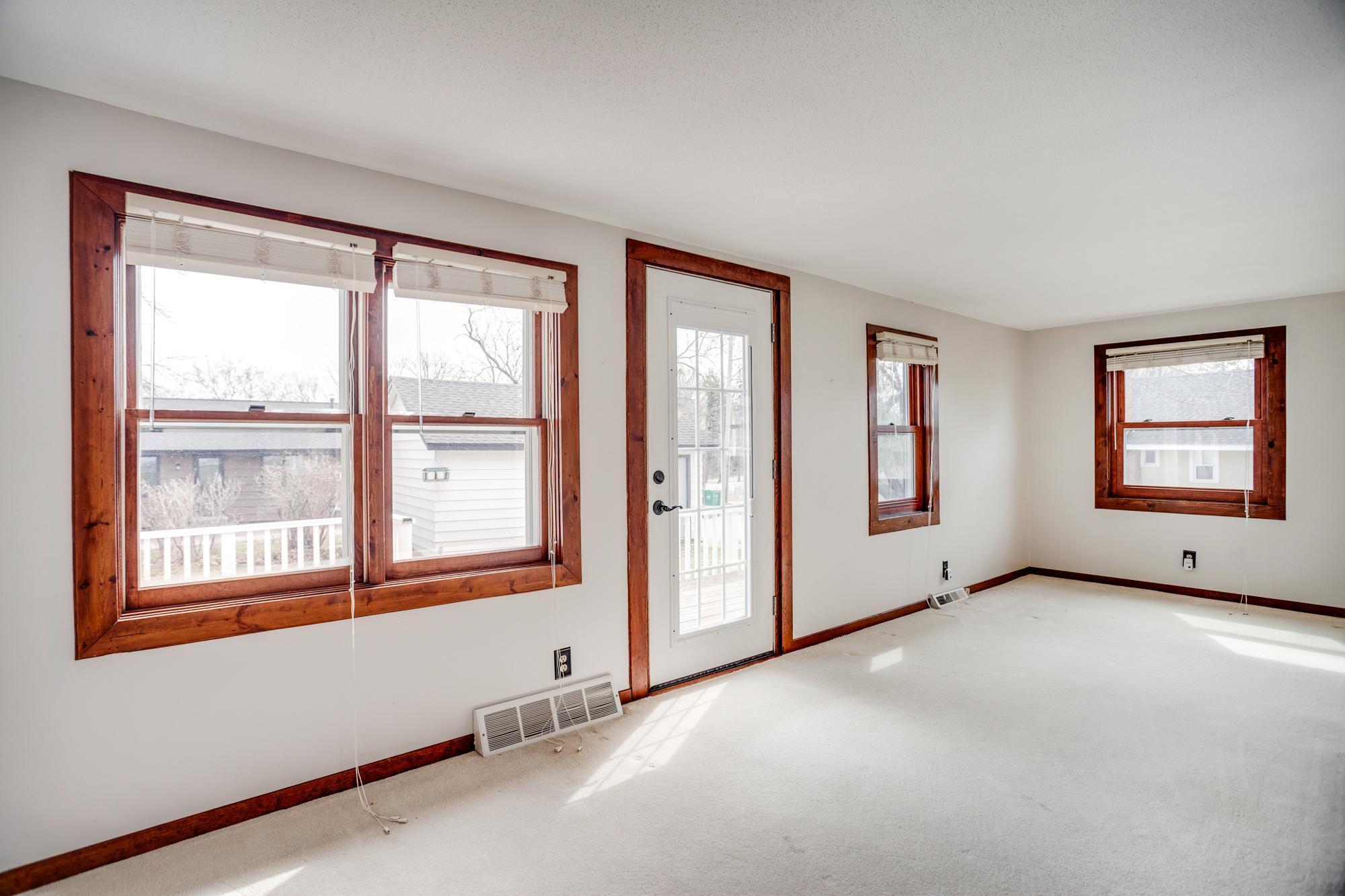 The entrance from the deck leads directly into the open main level gathering areas which include the living room and dining area, both bathed in natural light from multiple sides.