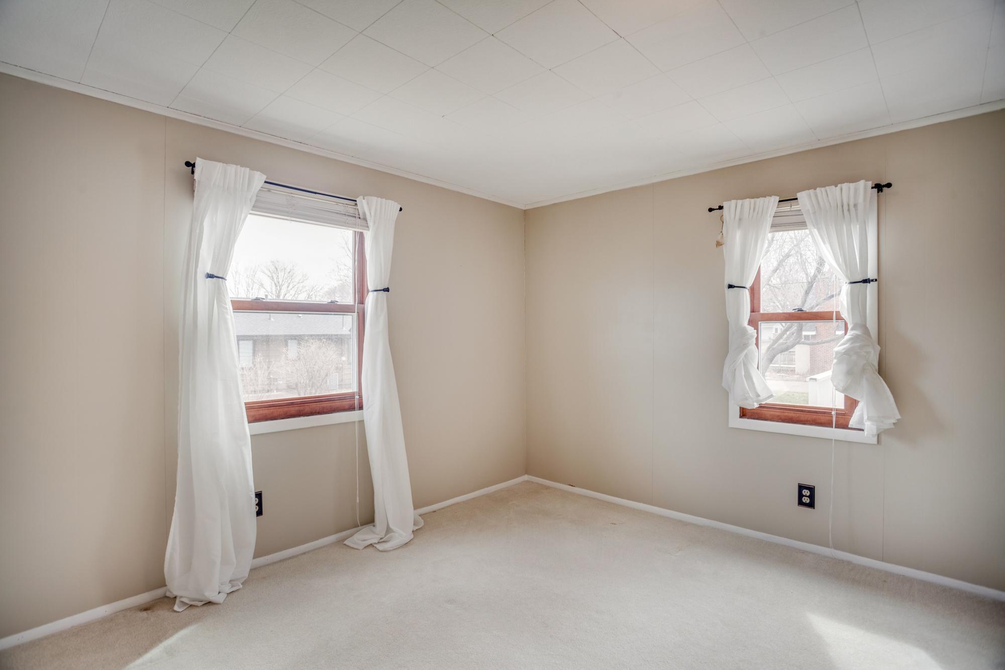 Bedroom 1 features neutral decor and multiple windows for light.