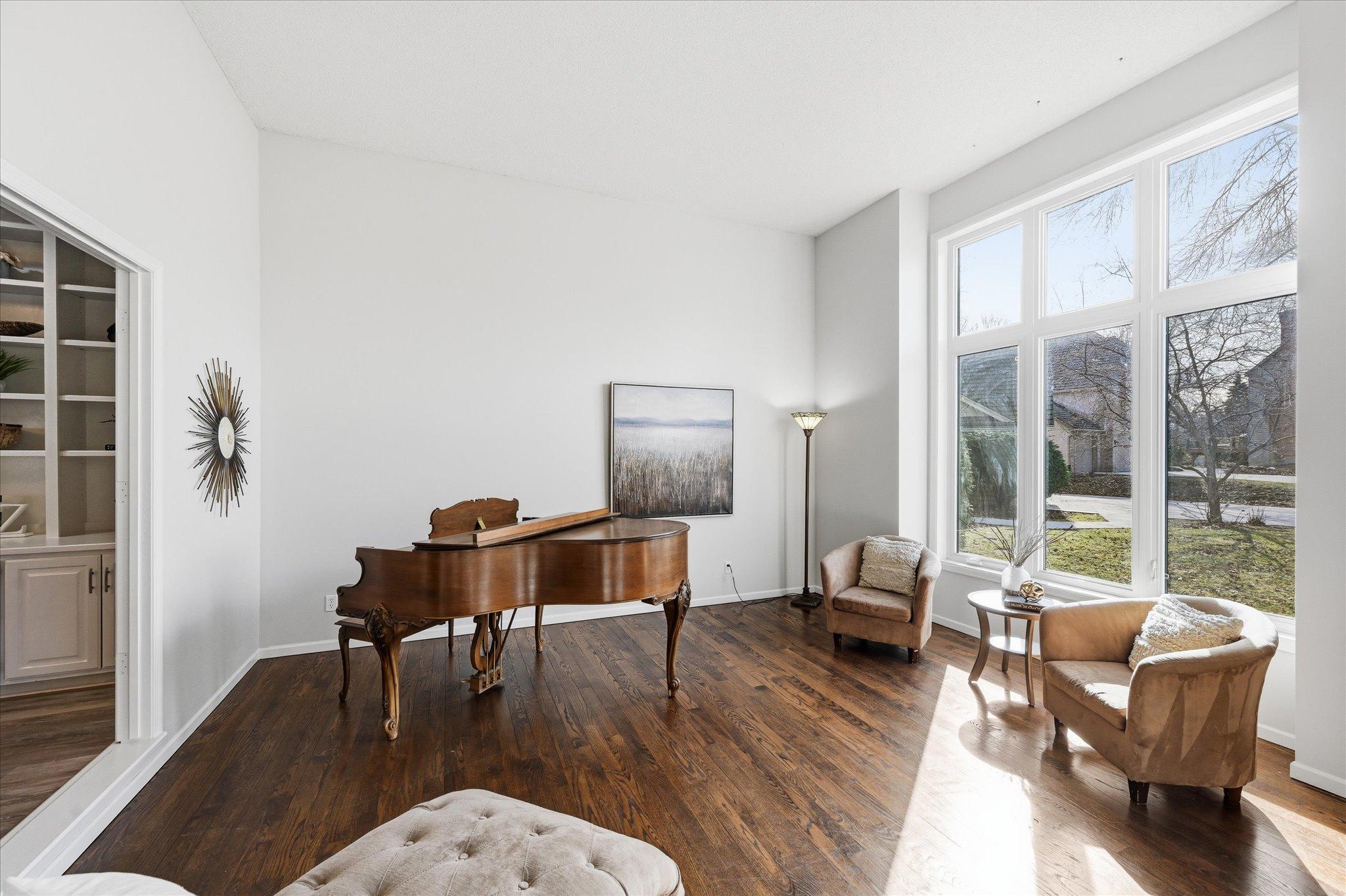 Formal living room with high ceiling and ample sunlight and newer windows.