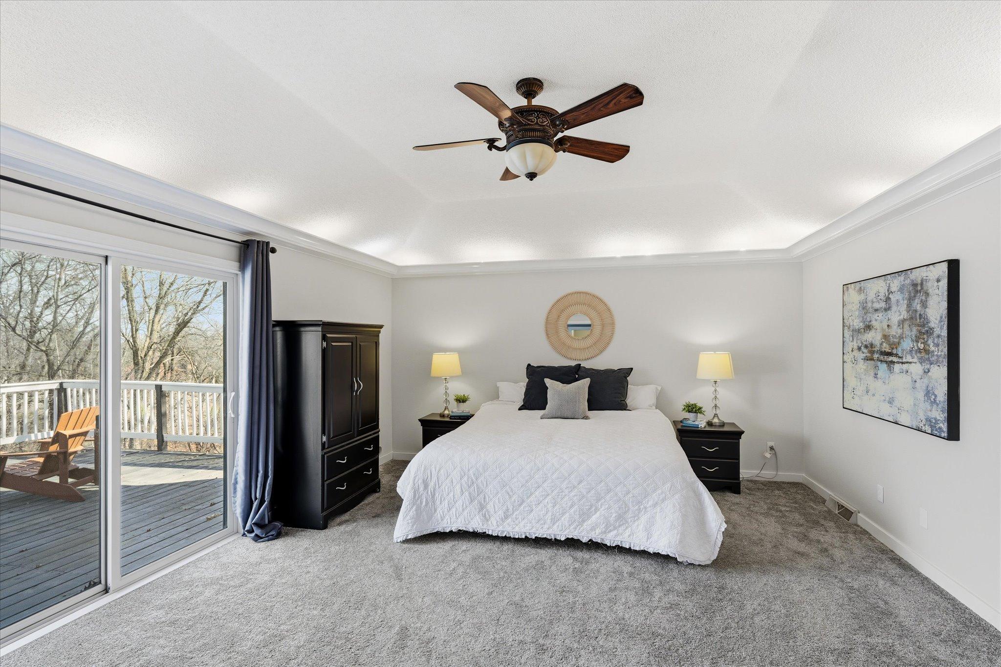 Primary view to the private deck and crown molding with mood lighting and raised tray vaulted ceiling