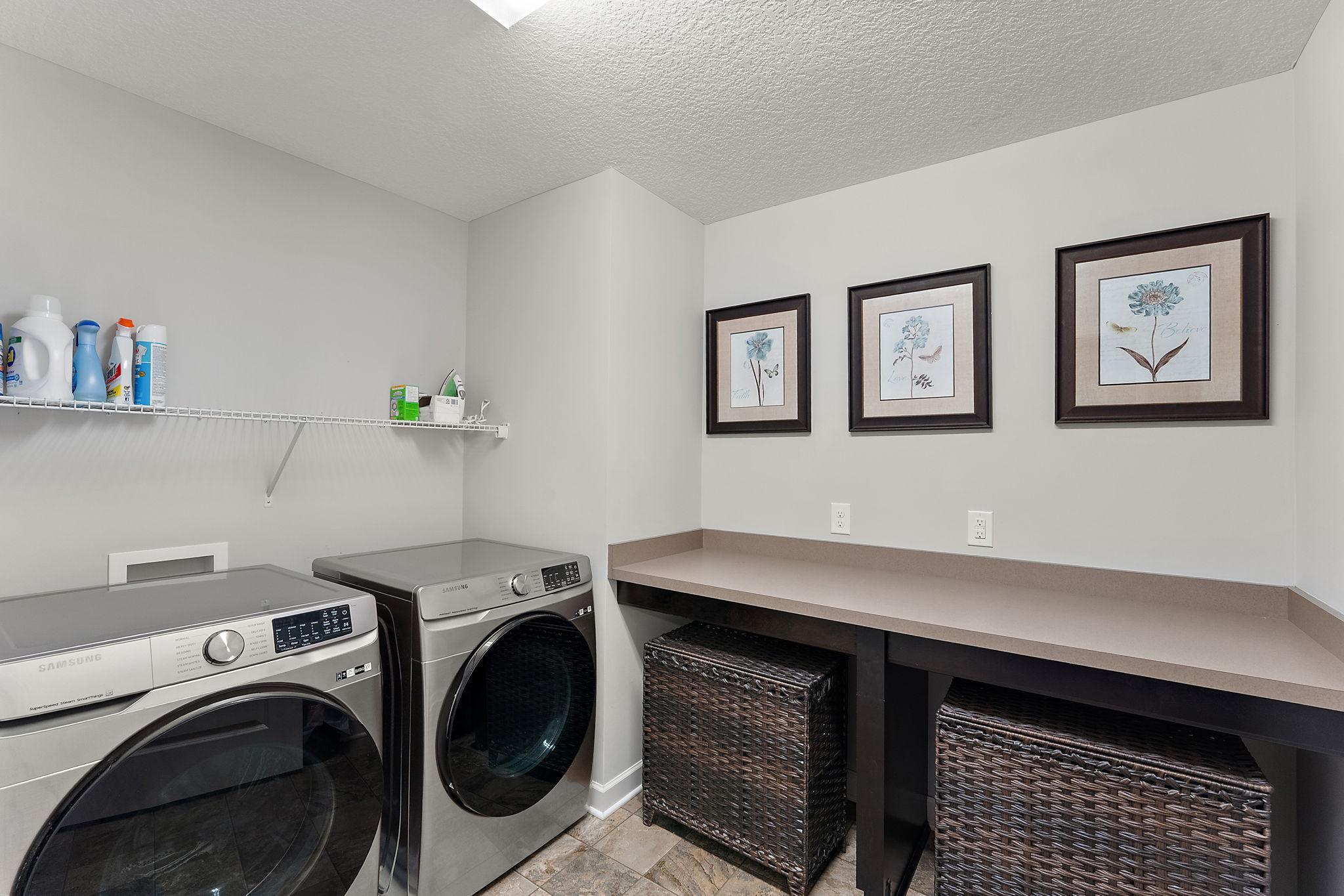 New washer and dryer in the laundry room, folding counter and shelf storage