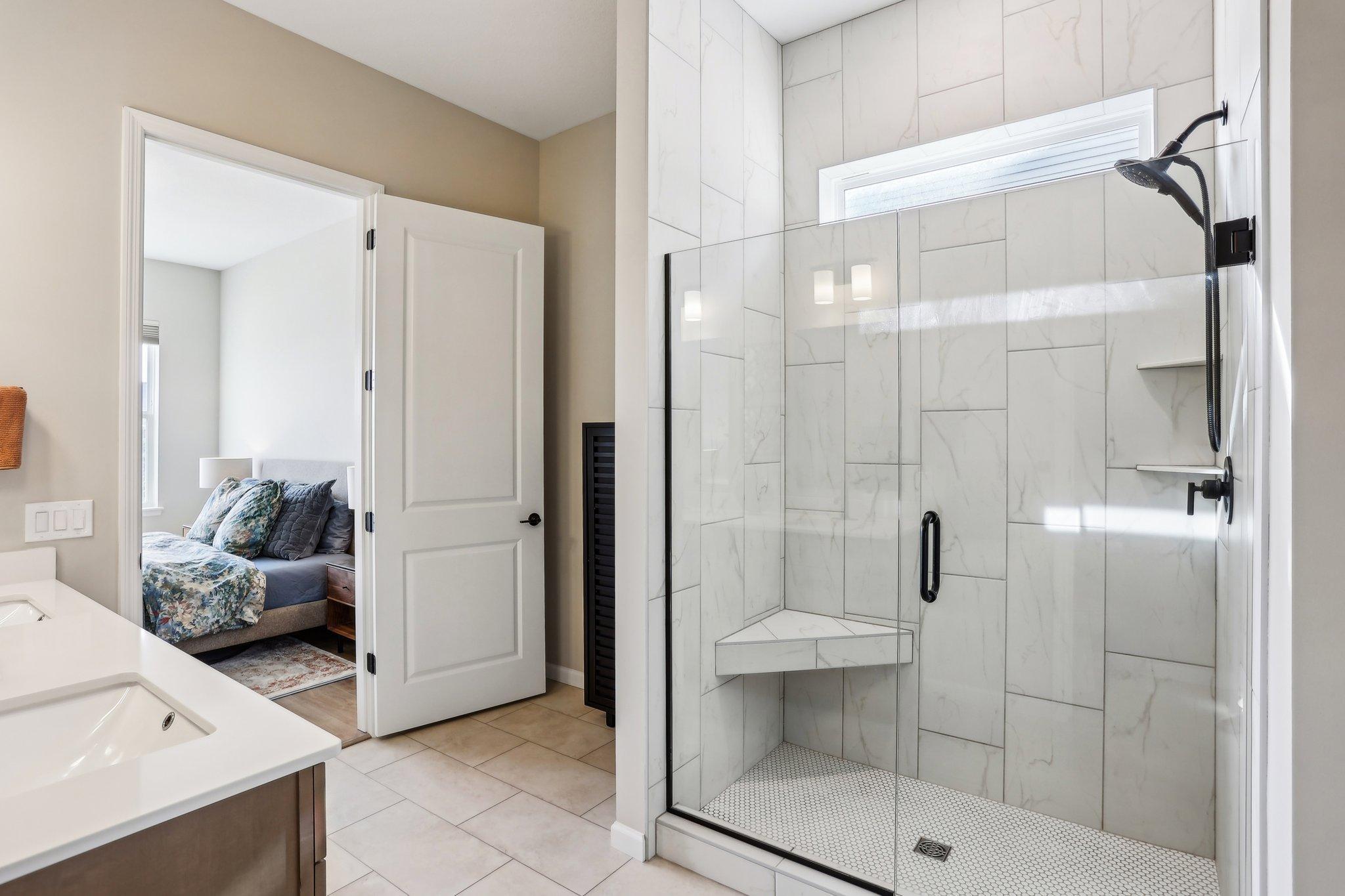 The primary bathroom features a spacious layout with modern finishes, including a large vanity, sleek fixtures, and a relaxing shower.