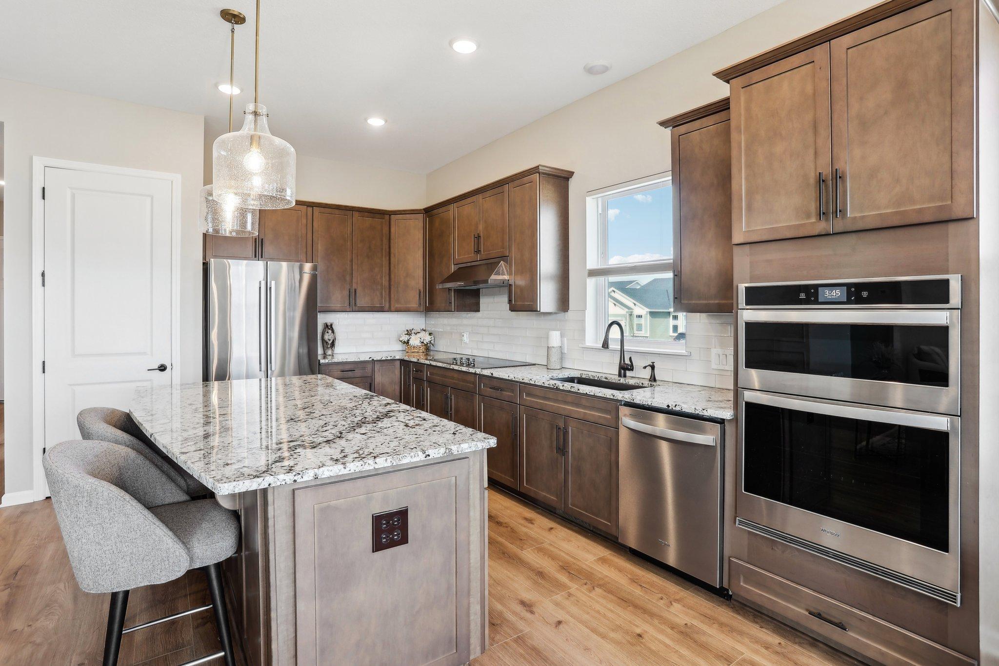 Sleek and stylish kitchen featuring stainless steel appliances, rich dark cabinetry, and abundant storage space.