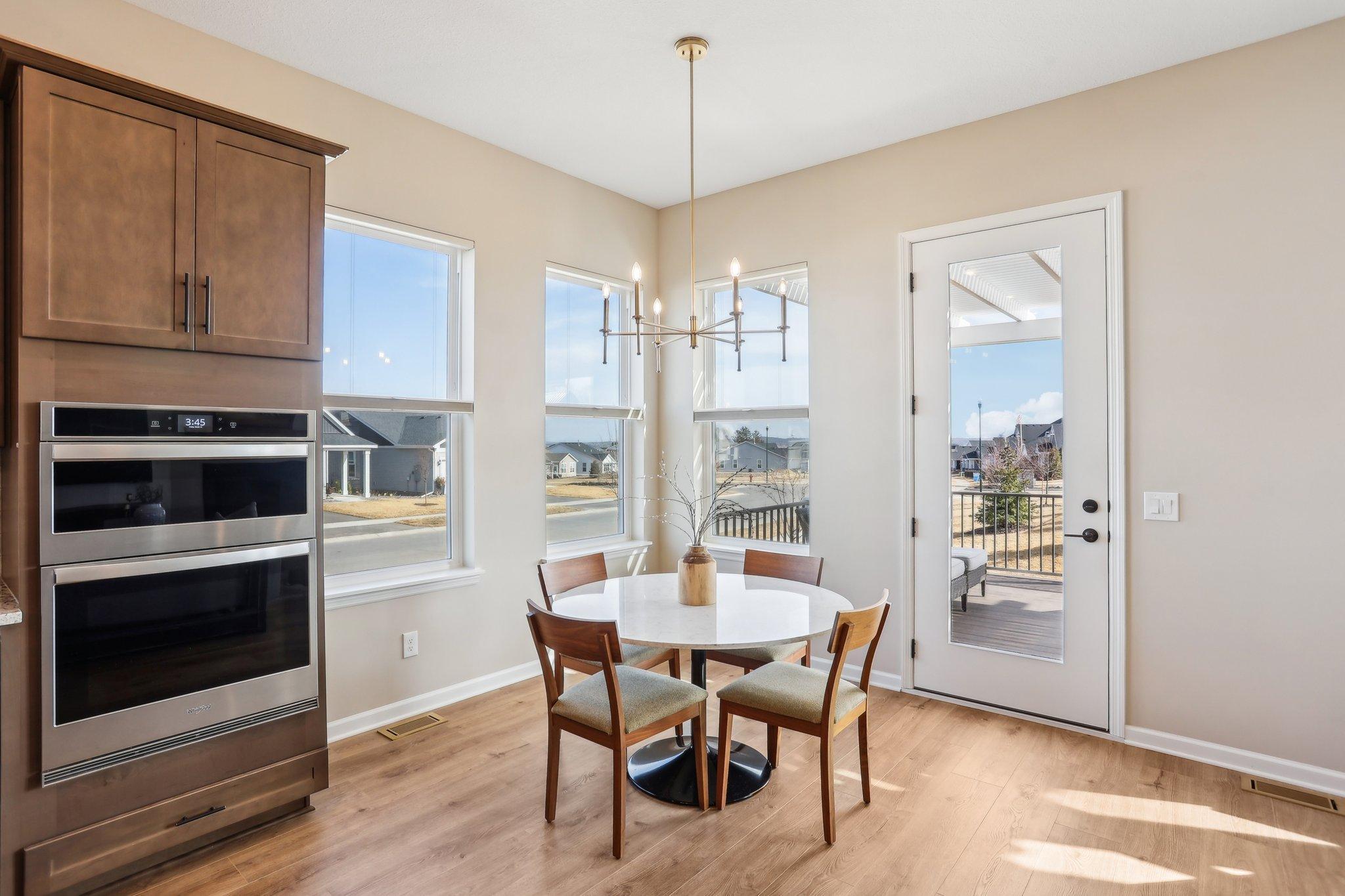 Dining area with views of the neighborhood through large windows and a door leading to outdoor patio, seamlessly blending indoor and outdoor living.