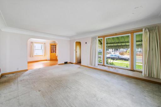 Large living room with an open flow into the formal dining area, highlighted by expansive bay windows that fill the space with natural light.