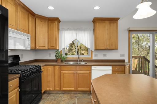 Natural light-filled kitchen with window & sliding glass door to deck.