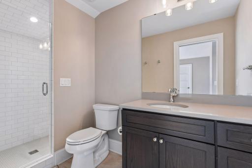 The bath features a large vanity and a fully tiled shower with frameless door