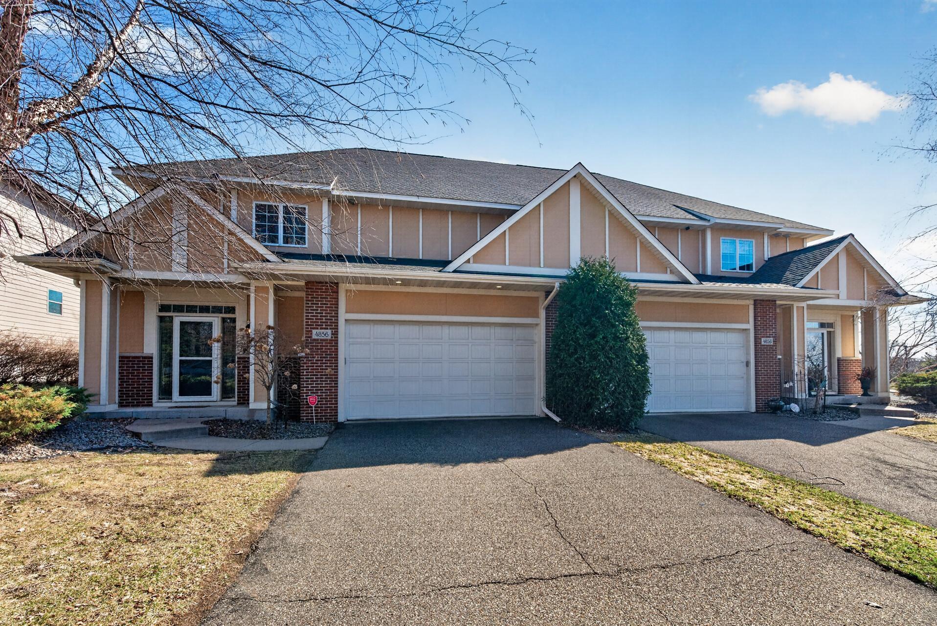 Spacious townhome-style exterior featuring a side-by-side 2-car garage and private driveway. Located in a clean, well-maintained community with convenient guest parking.