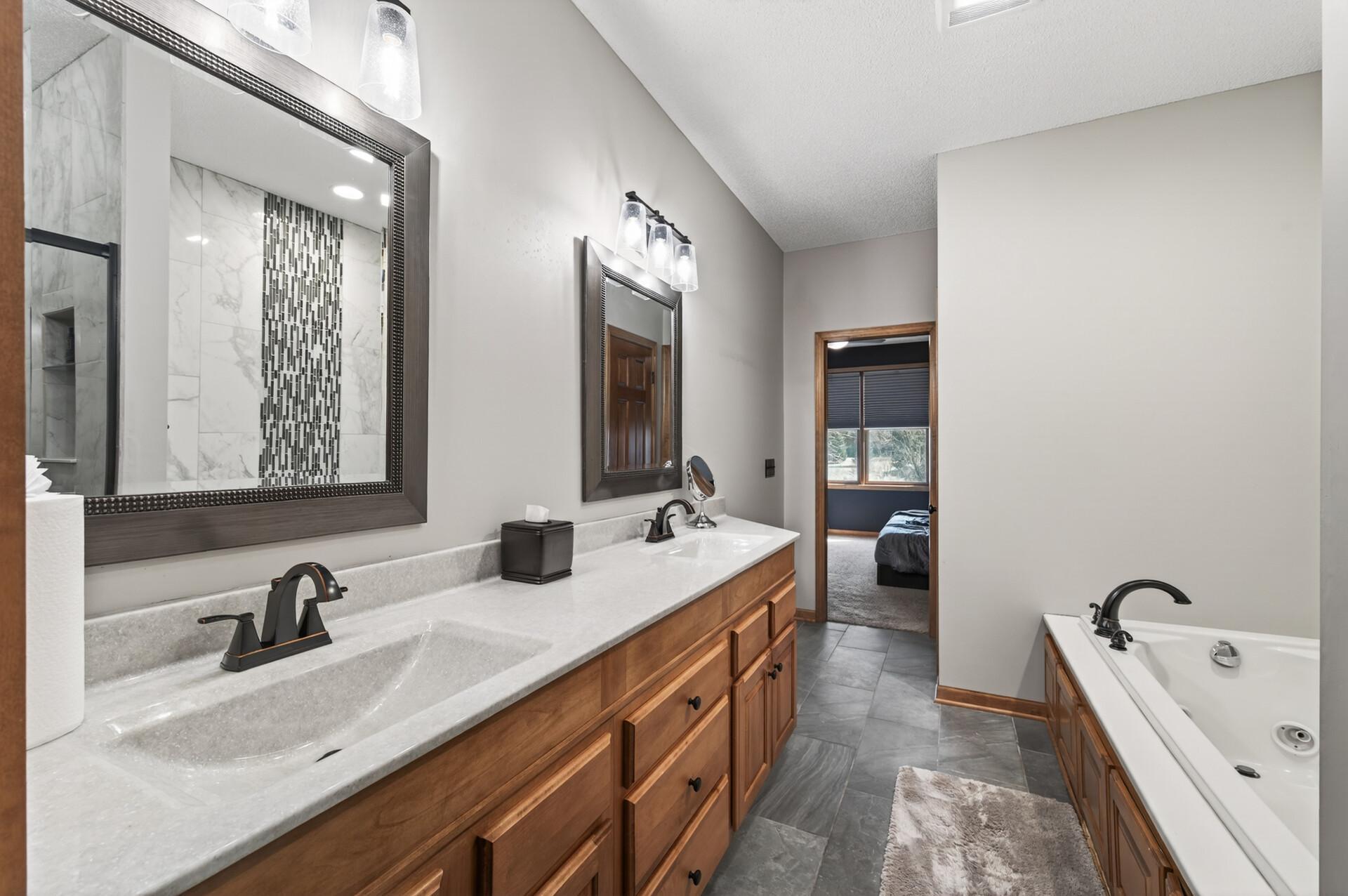 Double-sink vanity with solid surface countertops and ample cabinetry for storage. Clean lines and updated fixtures enhance the overall modern feel.