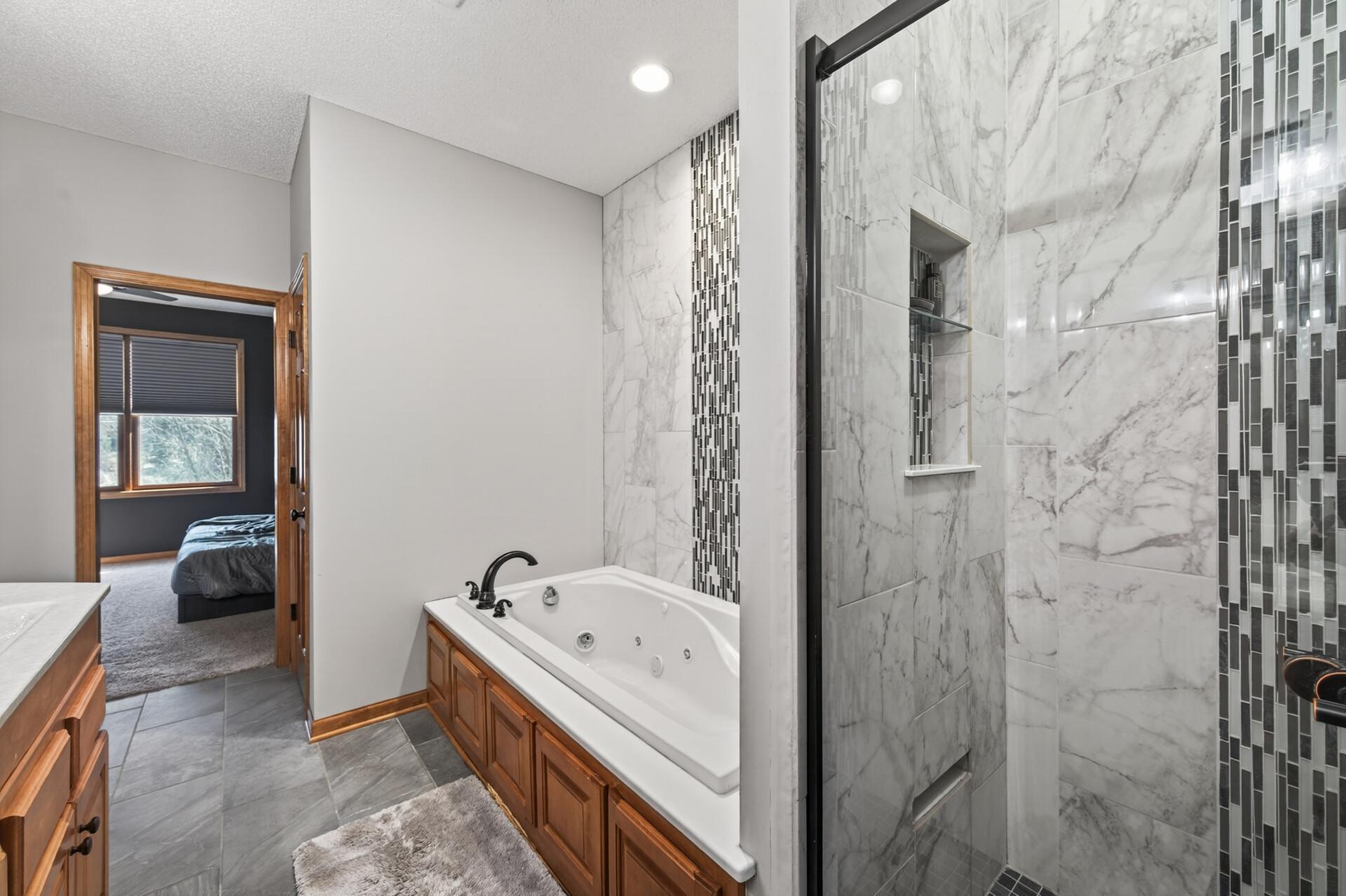 Walk-in tiled shower with glass enclosure and built-in niche, paired with a relaxing jetted tub. Designed for both everyday convenience and luxury.