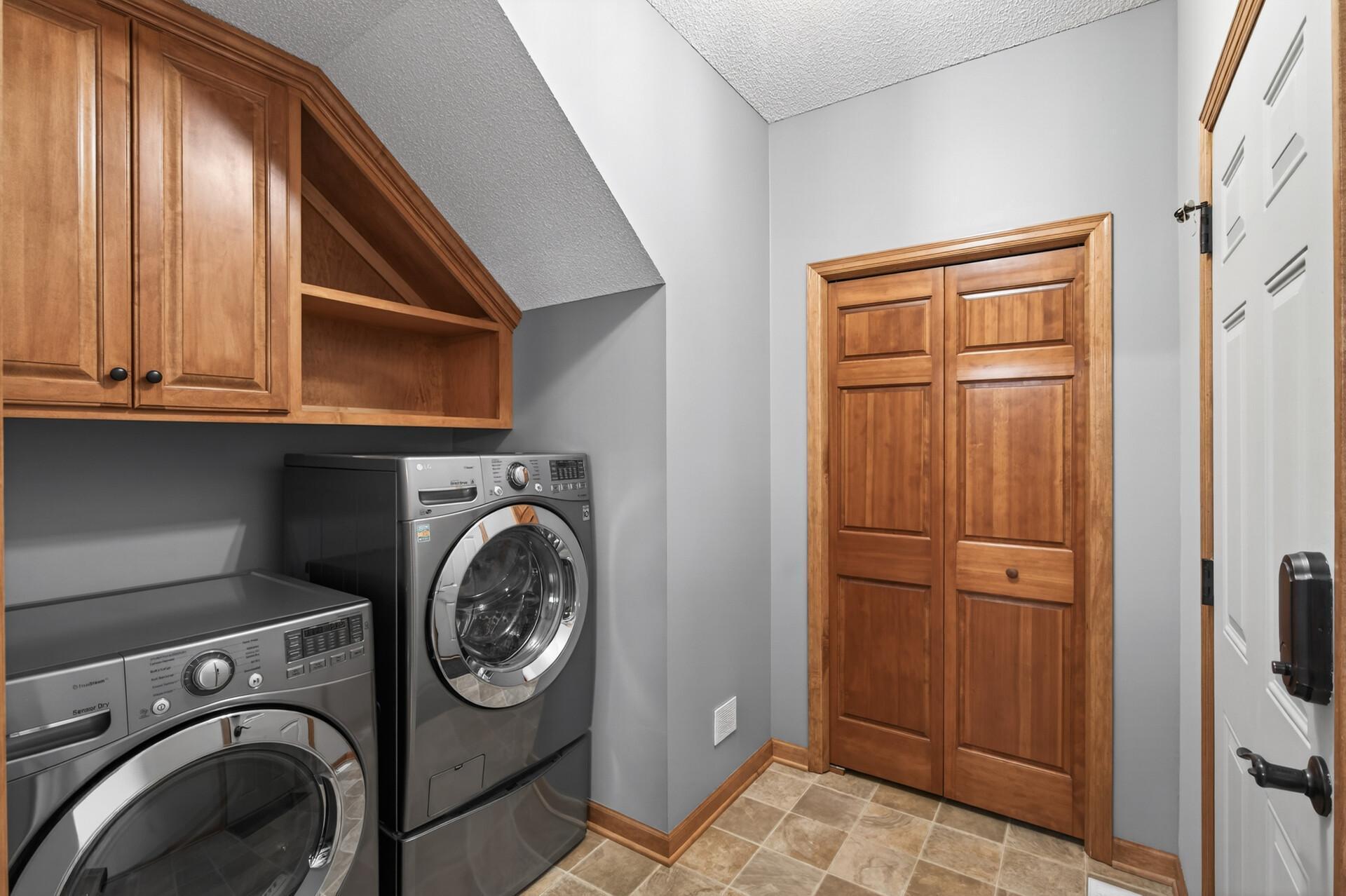 Convenient main level laundry area with upper cabinetry for storage, offering a practical and efficient layout.